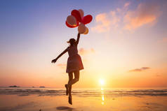 想象, 快乐的女孩跳跃与五颜六色的气球在日落在沙滩上, 飞, 跟随你的梦想