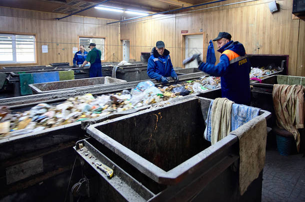 白俄罗斯格罗德诺-2018年10月: 4名穿制服的工人在废物处理厂工作, 从传送带上的垃圾中分选可回收材料.
