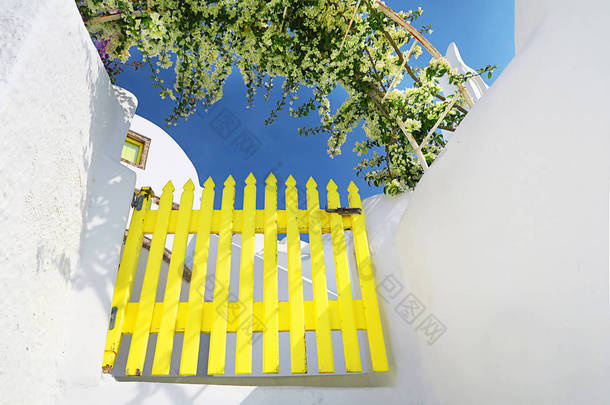 典型的美丽的希腊建筑在圣托里尼, 粉刷过的墙壁和黄色的大门, 美丽的花朵在大门, 蓝天, 欢乐的气氛, 幸福, 夏天和宁静, 伟大的度假目的地