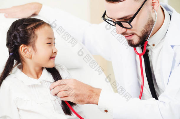 年轻的男医生在医院里检查小孩。这孩子很高兴, 不怕医生。医疗儿童保健概念.