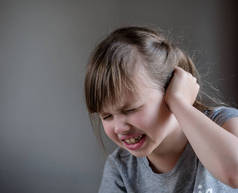 女孩有耳朵疼痛触摸他痛苦的头隔离在灰色背景
