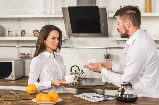 愉快的男朋友和女朋友在衬衫站在早上的咖啡在厨房, 性别平等的概念