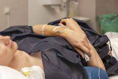 在产房里拿着滴管的女人, 按下遥控器, 定期进行硬膜外麻醉