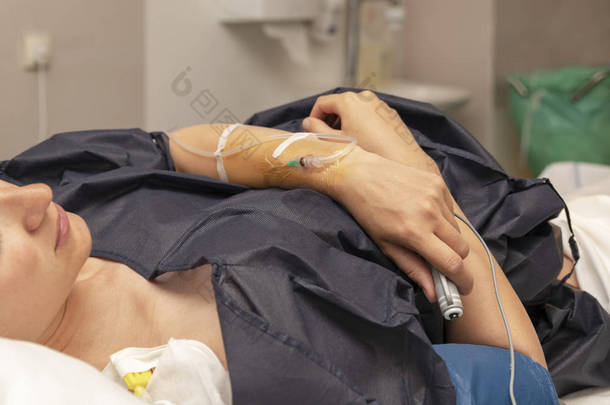 在产房里拿着滴管的女人, 按下遥控器, 定期进行硬膜外麻醉