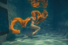 可爱的运动女孩游泳水下作为一个自由潜水员在纯粹的连身裤单独