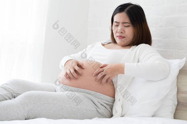 东南亚孕妇瘙痒的皮肤腹部, 导致条纹。妊娠妇女的问题与拉伸标记或条纹概念