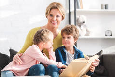 快乐的母亲微笑着在相机与孩子看书