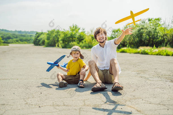 愉快的父亲和儿子玩玩具飞机与老跑道背景。带孩子旅行的概念