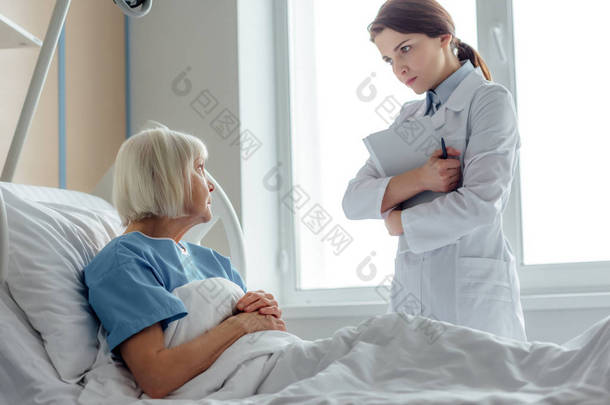 女医生拿着诊断和访问老年妇女躺在病床上