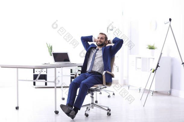 在工作场所坐在舒适的<strong>办公椅</strong>上的年轻商人