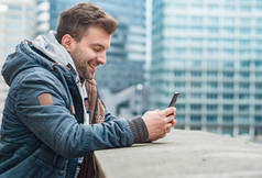 快乐的年轻人在他的手机上打字, 户外。拿着智能手机的一个小男孩的侧视图或个人资料
