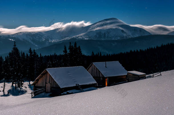 在月光下，喀尔巴阡山冬季的两座古老小屋