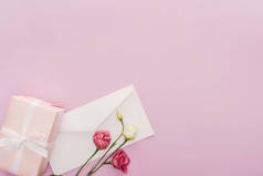 礼品盒、信封和鲜花的顶部视图, 在粉红色上与复制空间隔离