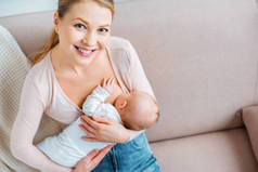 高视角快乐的年轻母亲母乳喂养婴儿和微笑在相机