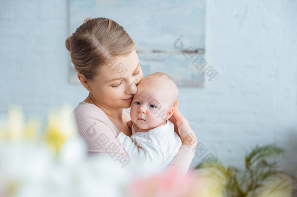 快乐的年轻母亲在家里抱着可爱的婴儿的<strong>选择性</strong>焦点
