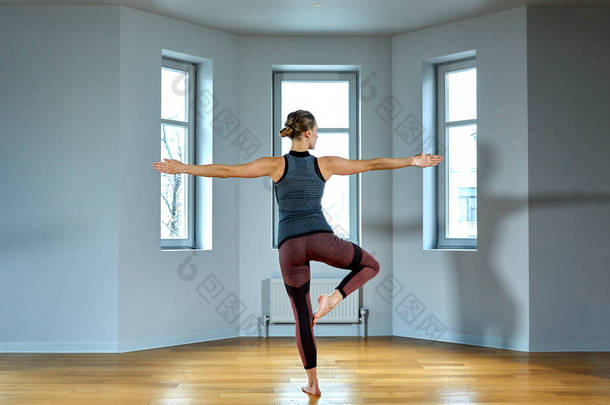 年轻的运动型女子练习<strong>瑜伽</strong>, 锻炼, 穿着运动<strong>服</strong>, 裤子和上衣, 室内关闭, <strong>瑜伽</strong>工作室。后视图