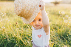 小婴儿女孩拿着草帽, 在夏季乡村散步日落