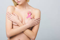 裁剪的裸体女孩与粉红色的乳腺癌意识丝带, 隔离在灰色的看法