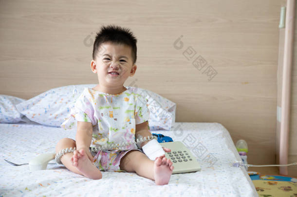 亚洲男婴微笑着穿上病人的西装, 坐在医院儿童科的房间里。患有传染病的儿童 ipd、侵袭性肺炎球菌病和2岁以下儿童