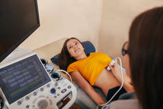 医生让病人妇女腹部超声。超声波扫描仪在医生的手中。诊断程序。超声检查