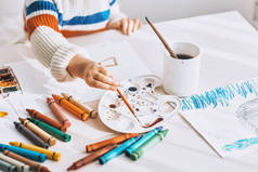 在家里的白色桌子上, 可以看到可爱的小女孩绘画和绘画的图片。漂亮的学龄前儿童在幼儿园画。人、童年和教育概念