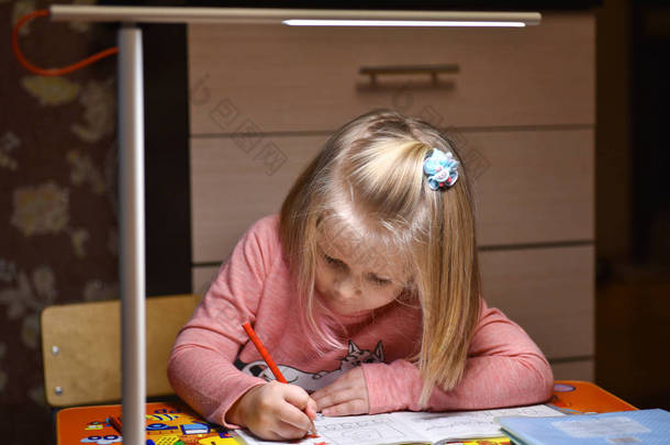 孩子学龄前<strong>儿童</strong>晚上在<strong>台灯</strong>的灯光下学会在家里的笔记本上画画和写字.