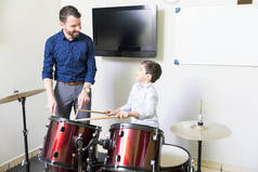 微笑的音乐老师教育男孩用他的鼓演奏技巧