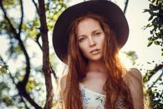 美丽的红头发年轻女子在一棵绿色的树荫下