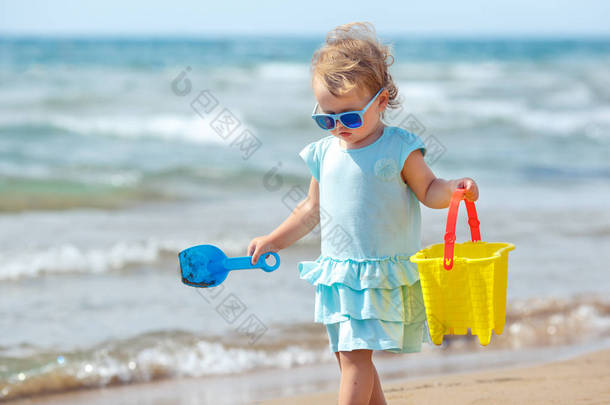 孩子们在热带海滩上玩耍。小女孩在海边挖沙子。孩子们玩沙类玩具。带着年幼的孩子旅行