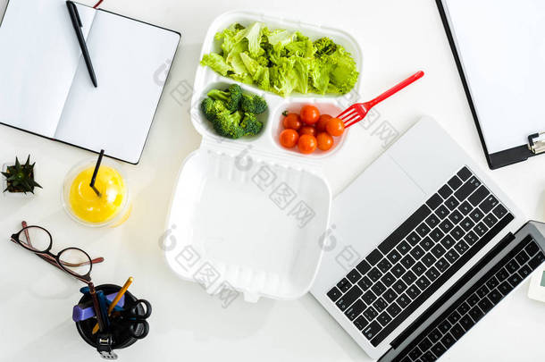在笔记本电脑和笔记本电脑附近可欣赏到美味蔬菜的顶部视图, 并提供复印空间