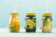 有机排毒饮料与浆果, 水果和草药在罐子与秸秆隔离在蓝色