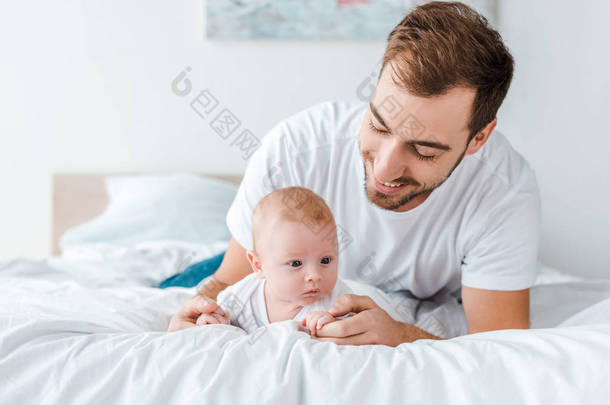 微笑的父亲躺在床上，婴儿在卧室