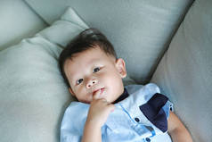 可爱的小亚洲男婴吮吸手指在嘴躺在灰色的桌子上.