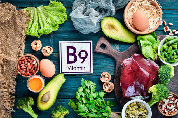 含有天然维生素B9的食物：肝脏、鳄梨、花椰菜、菠菜、欧芹、豆类、坚果，蓝色背景。顶部视图.