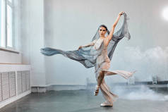 具有白色流线型面料的女芭蕾舞者。流动形态和运动.