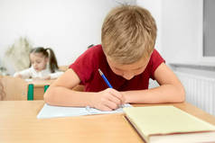 小学生坐在书桌前，用钢笔抄本写字.