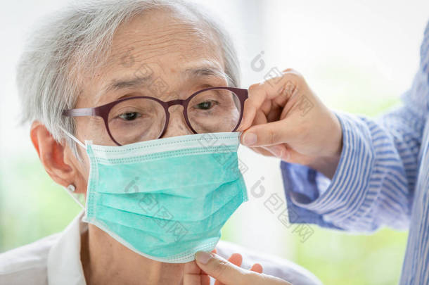 亚洲老年妇女因口罩保护咳嗽，老年妇女因空气污染而戴口罩，老人戴医面罩;污染观念、灰尘过敏及健康