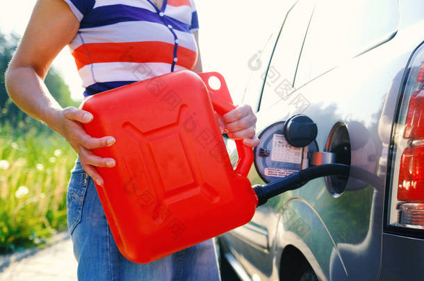 一个女人从备用油箱里给汽车加满汽油。10 升罐.