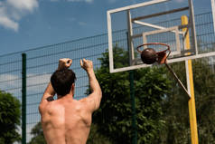 无衬衫篮球运动员在篮球场上投球的后视图