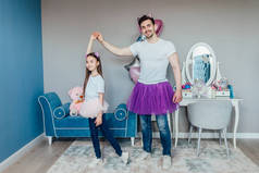 年轻的父亲和女儿站在房间里跳芭蕾舞，在一起消磨时光