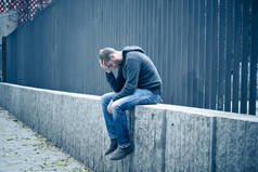 患有抑郁症的年轻有魅力的男人独自坐在大街上, 在失业中感到焦虑和孤独的年轻的有魅力的男人.