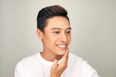 无衬衫的年轻英俊的亚洲男子检查他的脸皮肤护理和美容概念的白色背景的肖像