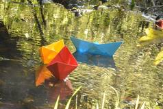 不同颜色的纸船在一条小溪中游泳,它映着深秋的太阳——在深秋的湖面上,略显模糊的纸船在湖面上涂上鲜艳的色彩