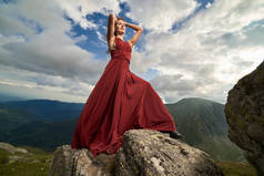 美丽的女性时装模特在山岩上的红色礼服