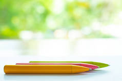 模糊 3 彩色笔 ( 黄色, 粉红色, 绿色 ) 在白纸上, 博克绿色花园背景, 笔记本, 特写 & 微距拍摄, 选择性焦点, 通信, 文具概念