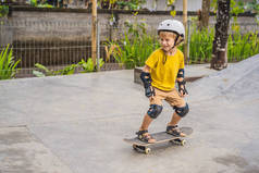 戴着头盔和膝盖垫的运动男孩在滑板公园里学习滑板。儿童教育、体育