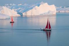 在极地夏季的午夜阳光季节，小红船在迪斯科湾冰川的浮冰中巡航。格陵兰的Ilulissat 。南极海冰山探险船