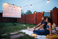 情侣在爱看电影，在黄昏，外面的草坪上的庭院