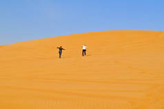 两个人穿越沙漠。活跃在迪拜的假期。无边无际的沙地沙漠.