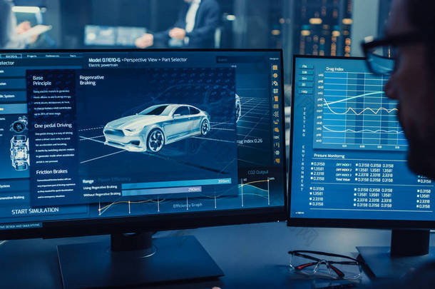 专业工程师使用 3d Cad 软件在计算机上工作，并在高科技开发实验室中测试电动汽车底盘原型，并配有车轮、电池和发动机.